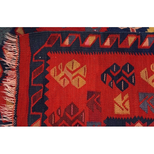 2214 - A Kilim runner, 20th century, the red field with a central section decorated with animals, within a ... 