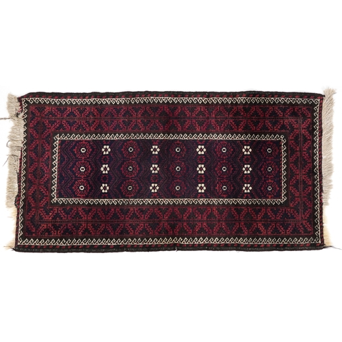 2212 - A Baluch rug, 20th century, the midnight blue field with a central rectangular panel within a comple... 