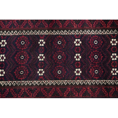 2212 - A Baluch rug, 20th century, the midnight blue field with a central rectangular panel within a comple... 