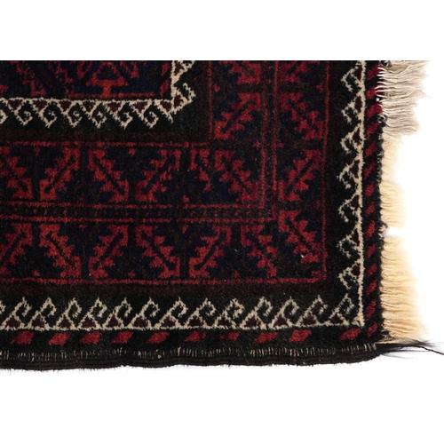 2212 - A Baluch rug, 20th century, the midnight blue field with a central rectangular panel within a comple... 