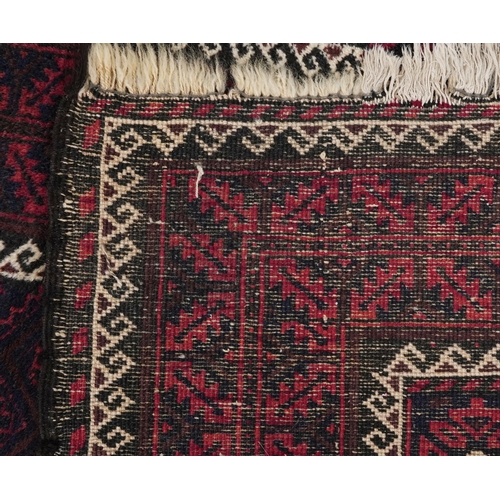 2212 - A Baluch rug, 20th century, the midnight blue field with a central rectangular panel within a comple... 