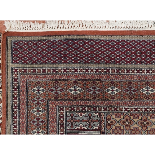2225 - A Pakistani carpet, late 20th century, the salmon pink field with a central stylized medallion withi... 