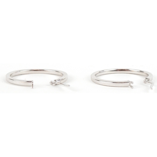 3096 - A pair of as new 9ct white gold hoop earrings retailed by Goldsmiths, with box, 2.6cm in diameter, t... 