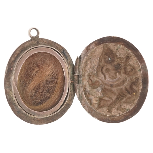 3381 - An Indian unmarked silver locket decorated in repoussé with a deity, 3cm high, 13.9g.