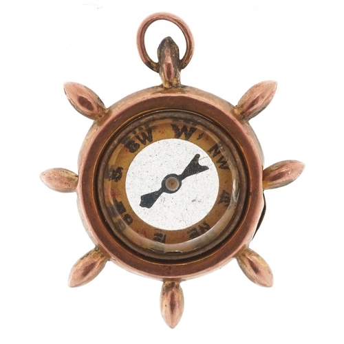 3250 - A 9ct gold compass charm in the form of a ship's wheel, 2.5cm in diameter, 2.9g.