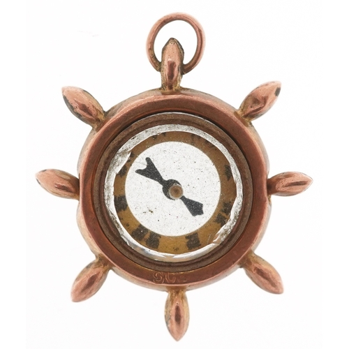 3250 - A 9ct gold compass charm in the form of a ship's wheel, 2.5cm in diameter, 2.9g.