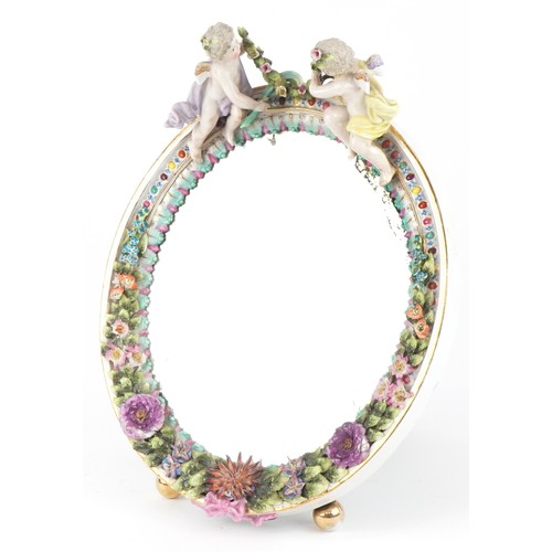 27 - A Sitzendorf German porcelain oval easel mirror with encrusted floral decoration and surmounted with... 