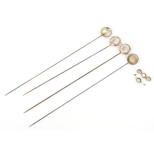 1044 - A set of four gold plated and mother-of-pearl hatpins, buttons and a broken brooch, the pins 24.5cm ... 