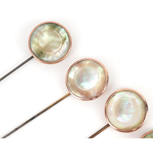 1044 - A set of four gold plated and mother-of-pearl hatpins, buttons and a broken brooch, the pins 24.5cm ... 