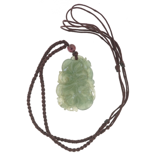 3446 - A Chinese naturalistic carved green stone pendant on a cord necklace, tests as jade, the pendant 3.5... 