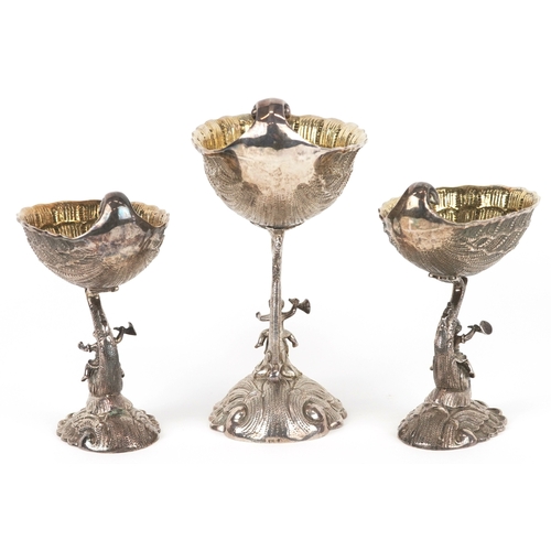  xxx side view xx Three silver open salts cast as Putti riding dolphins, with shell design bowls, the... 
