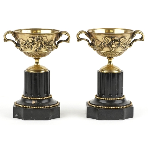 50 - A pair of 19th century bronze twin handled urns decorated in relief with swags of vines and berries,... 