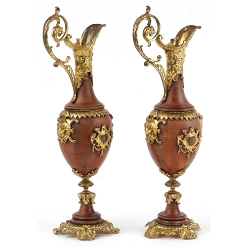  A pair of 20th century turned mahogany and gilt metal mounted decorative ewers, the scroll handles a... 