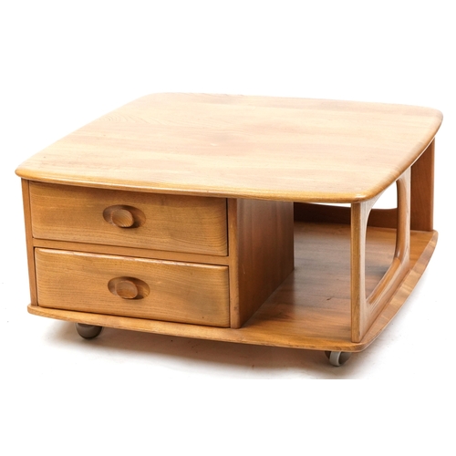 1010 - An Ercol elm square coffee table fitted with a drawer and open shelves, on casters, 41cm H x 78cm W ... 