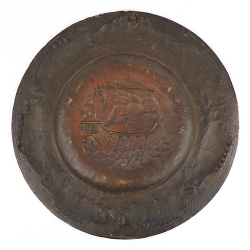 14 - An Arts & Crafts brass wall hanging charger embossed with a sailing ship and fish, 61cm in diameter.