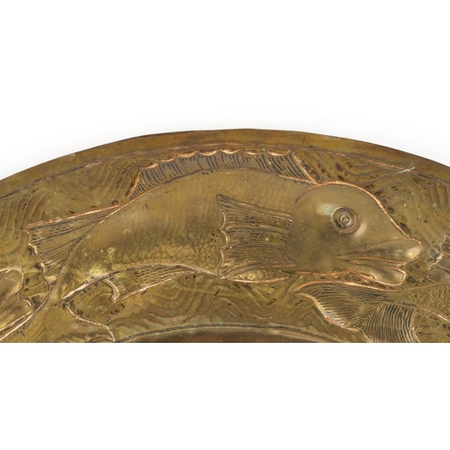 14 - An Arts & Crafts brass wall hanging charger embossed with a sailing ship and fish, 61cm in diameter.