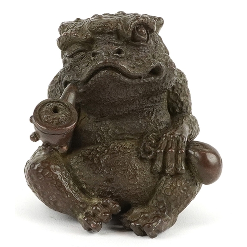 172 - A Japanese patinated bronze study of a seated toad smoking a pipe, impressed character marks to the ... 