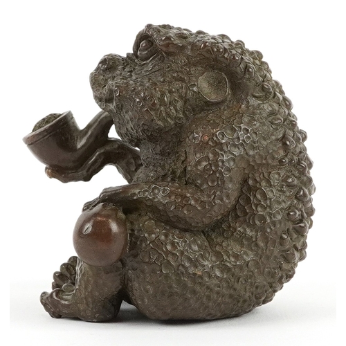172 - A Japanese patinated bronze study of a seated toad smoking a pipe, impressed character marks to the ... 