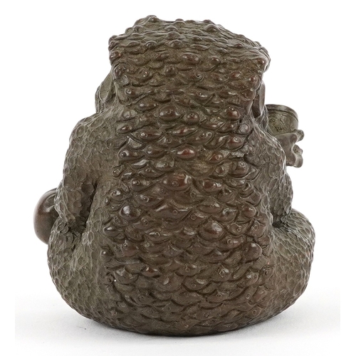 172 - A Japanese patinated bronze study of a seated toad smoking a pipe, impressed character marks to the ... 
