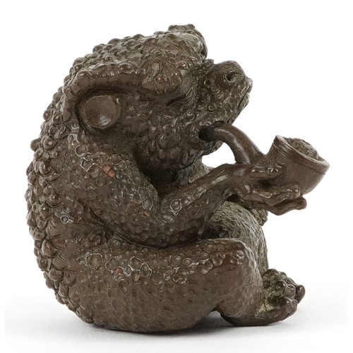 172 - A Japanese patinated bronze study of a seated toad smoking a pipe, impressed character marks to the ... 