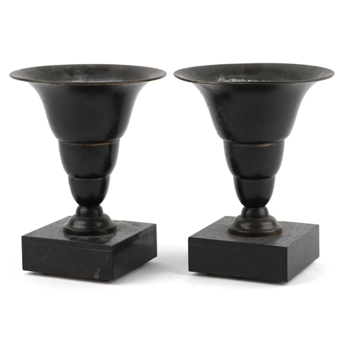 53 - A pair of bronzed vase garnitures raised on black slate and onyx bases, 22.5cm high.