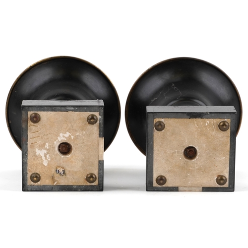 53 - A pair of bronzed vase garnitures raised on black slate and onyx bases, 22.5cm high.