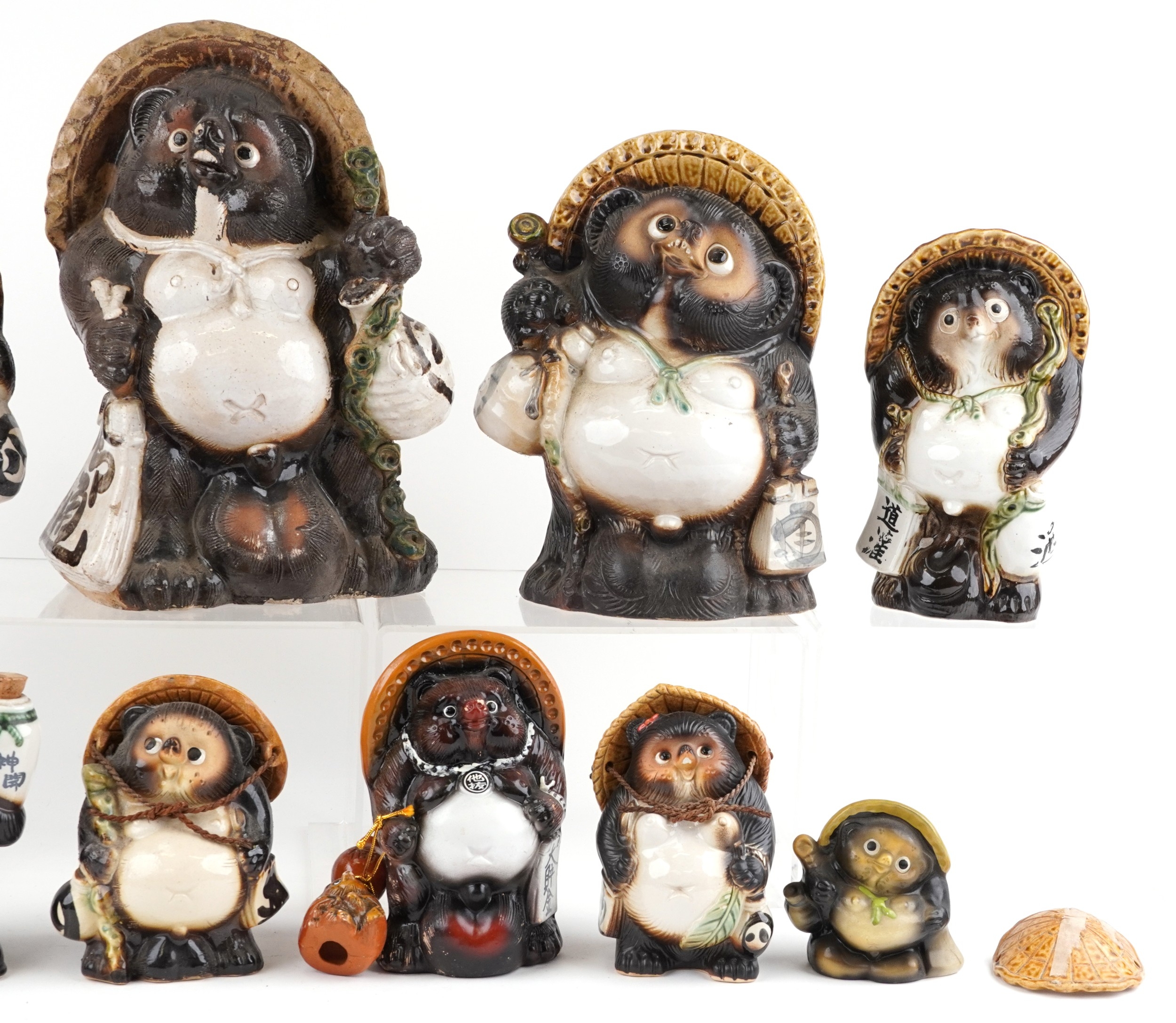Nine Japanese pottery Tanuki figures and a Black Forest style bottle ...