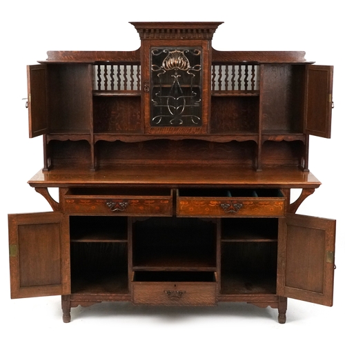  Shapland and Petter an Arts & Crafts oak sideboard with inlaid floral decoration, the dental moulded... 