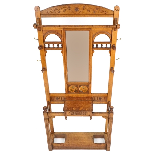  Arts & Crafts oak hall stand with carved and hand painted decoration, the mirrored back above a brus... 