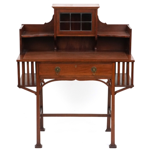  An Arts & Crafts mahogany desk, the shelf back with a leaded glass door above a frieze drawer, raise... 