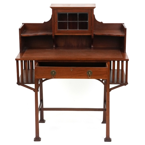  An Arts & Crafts mahogany desk, the shelf back with a leaded glass door above a frieze drawer, raise... 