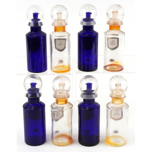 83 - Eight Royal Pharmaceutical Society coloured glass chemist bottles with domed lids, each bearing a gi... 
