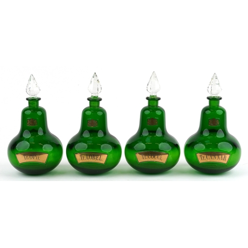 73 - A set of four Royal Pharmaceutical Society emerald glass apothecary bottles with cut glass stoppers,... 