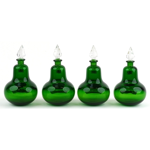 73 - A set of four Royal Pharmaceutical Society emerald glass apothecary bottles with cut glass stoppers,... 