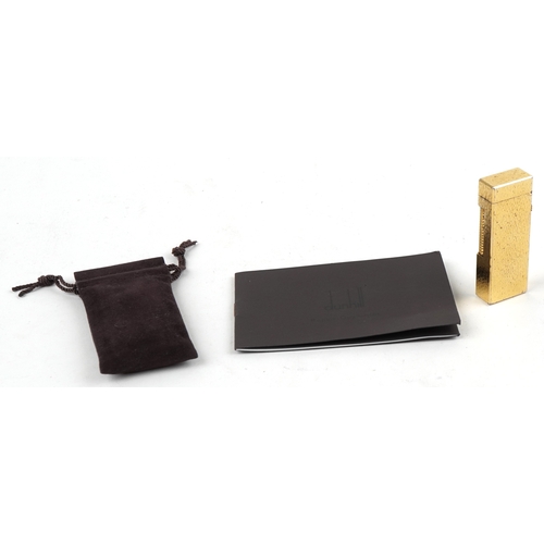 100 - A Dunhill gold plated engine turned pocket lighter with guarantee card, 6.5cm high.