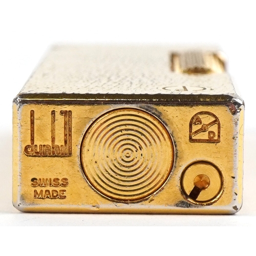 100 - A Dunhill gold plated engine turned pocket lighter with guarantee card, 6.5cm high.