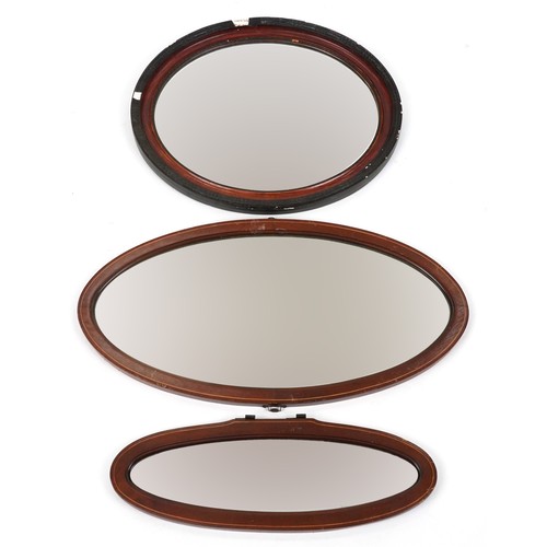 Three oval mahogany framed mirrors, two with line inlay, the largest ...