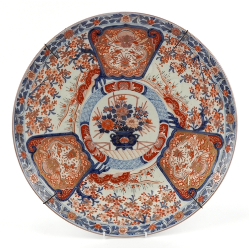 Large Japanese Imari porcelain charger hand painted with a central cartouche of flowers surrounded by three panels of dragons, character marks to the base, 47cm in diameter.