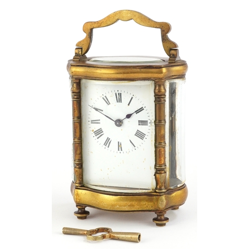 76 - Gilt brass serpentine glass carriage clock having enamelled dial with Roman numerals, 13cm high.