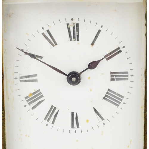 76 - Gilt brass serpentine glass carriage clock having enamelled dial with Roman numerals, 13cm high.