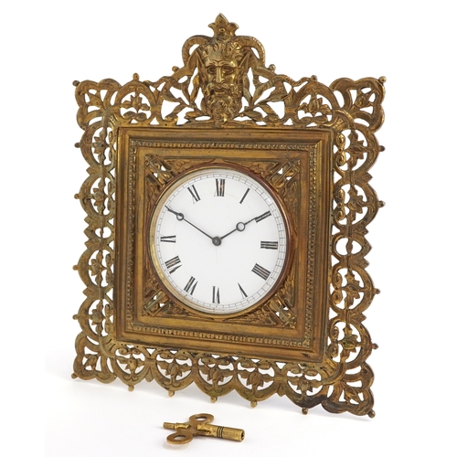 214 - Antique brass strut clock embossed with masks and engraved with fish, the enamelled dial having Roma... 