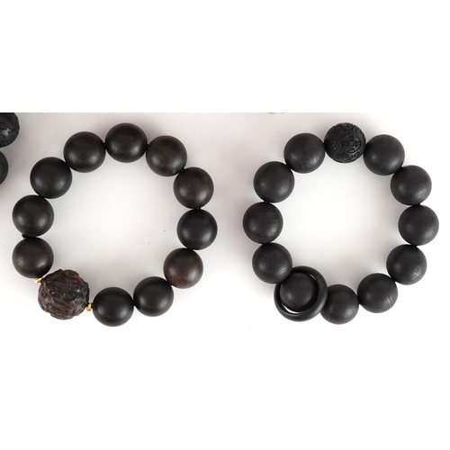 Four Chinese carved wooden bead bracelets, two with Chinese coin motifs ...