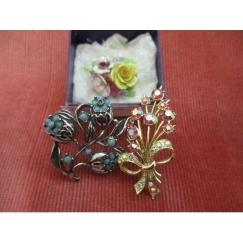 22 - 3 BROOCHES 1 FLORAL BONE CHINA BROOCH AND TWO METAL BROOCHES ONE PINK COLOURED STONES THE OTHER WITH... 