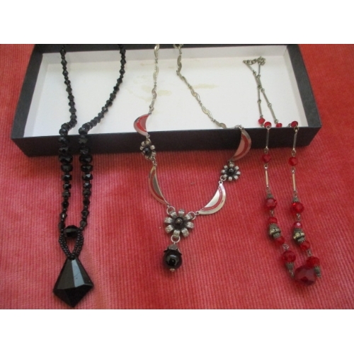 25 - A BOX OF 3 NECKLACES ONE BLACK GLASS BEADED NECKLACE, RED GLASS BEAD WITH CHAIN LINK AND ONE OTHER