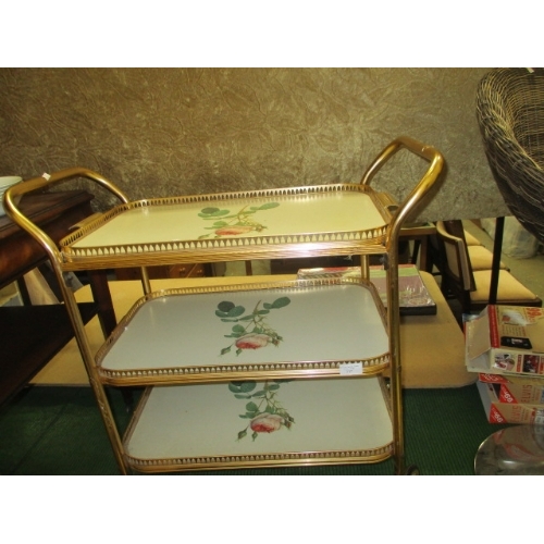 317 - VINTAGE SERVING TROLLEY IN GOLD METAL ON CASTERS , 3 TRAYS IN CREAM WITH ROSE DETAIL