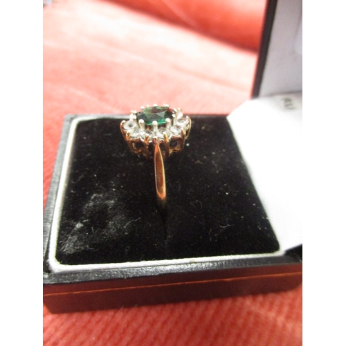 27 - 9CT GOLD RING WITH A GREEN CENTRE STONE SURROUNDED BY CLEAR STONES, SIZE L