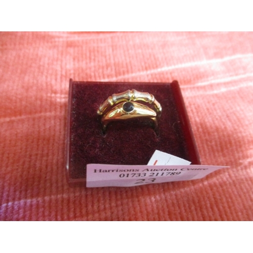 23 - 2 X GOLD COLOURED RINGS ONE WITH BLACK STONE