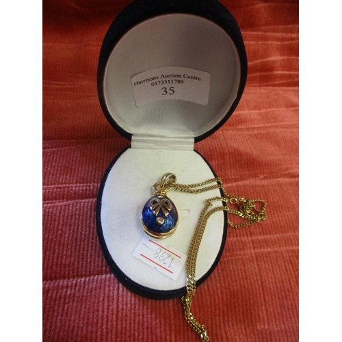 35 - GOLD COLOURED CHAIN AND  EGG SHAPED PENDANT WITH BLUE ENAMEL AND  GOLD COLOURED BOW PATTERN WITH 2 W... 