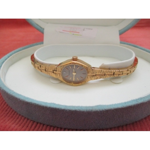 12 - LADIES GOLD COLOURED ACCURIST WATCH WITH WHITE STONE INDICATING 12 ON THE FACE BOXED