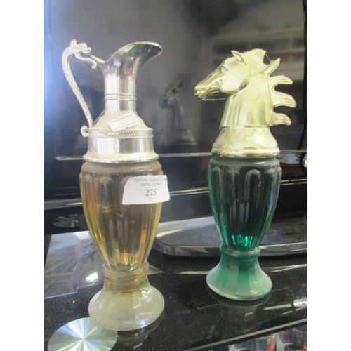275 - AN AMBER COLOURED GLASS JUG WITH SILVER METAL SPOUT AND A GREEN GLASS DECANTER WITH METAL TOP
